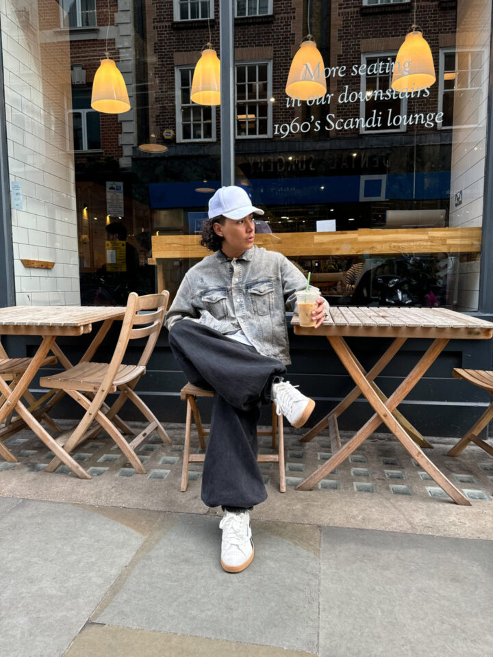 Person sat outside coffee shop with white reebok trainers
