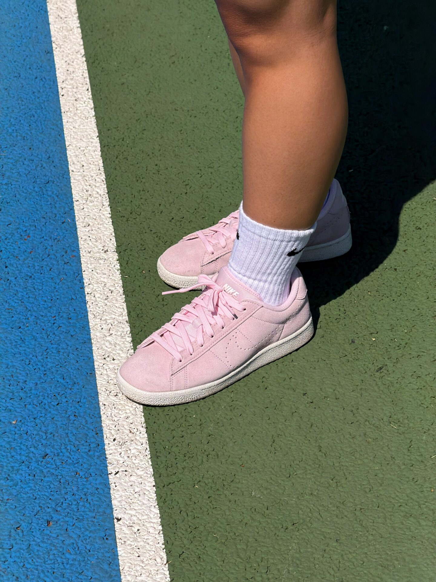 A close-up shot of a person wearing the Nike Tennis Classic trainers in pink.