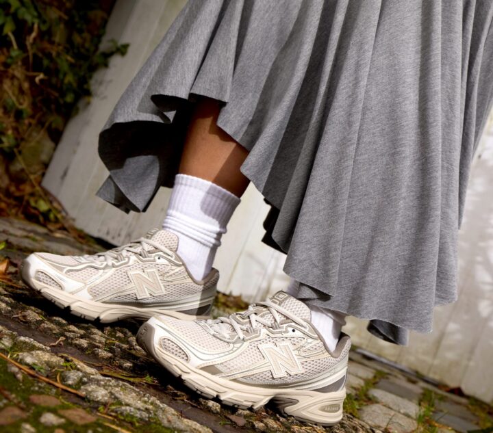 Person standing outside wearing beige New Balance 740 trainers with a long grey skirt.