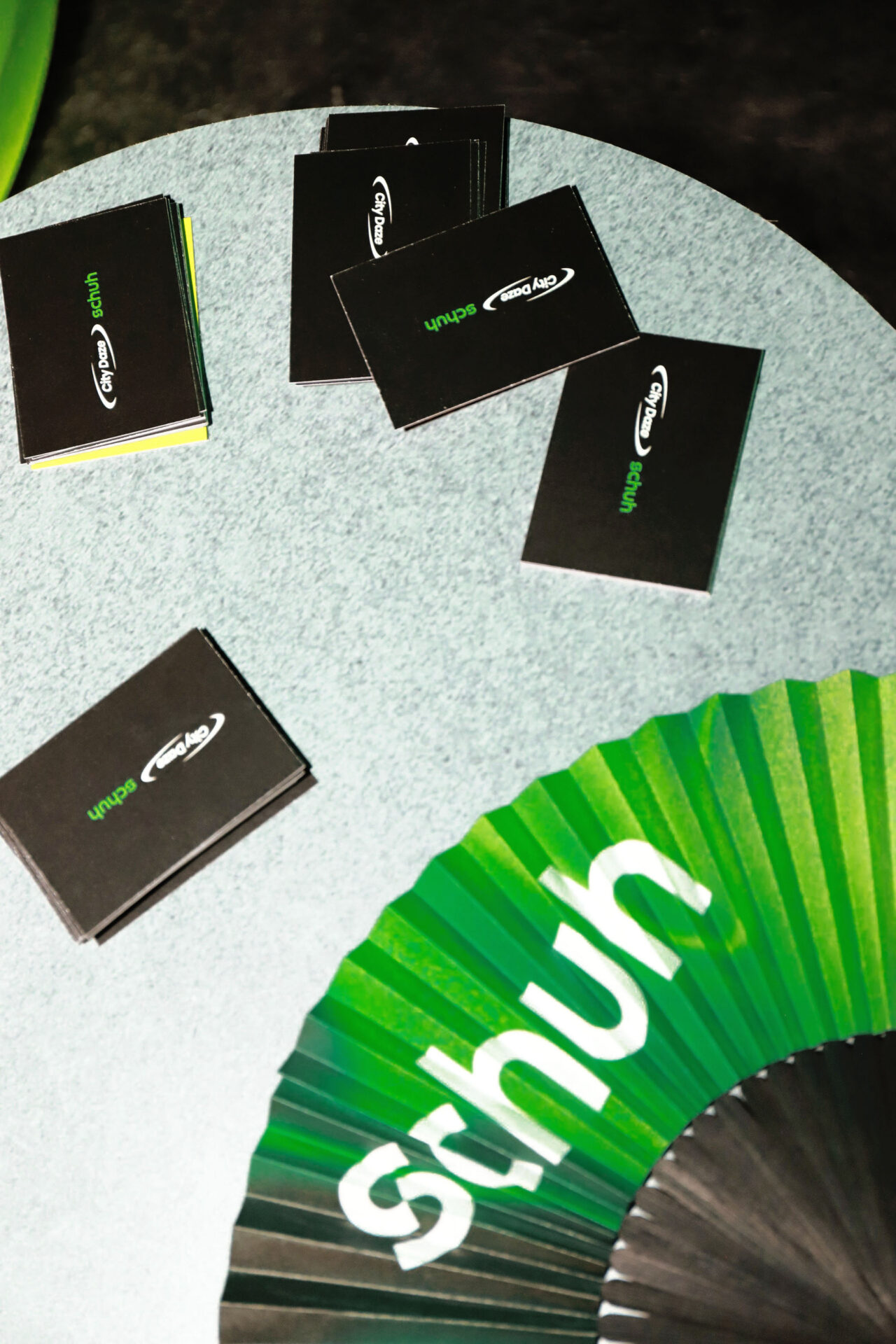 A schuh branded fan sitting on a table next to some schuh x City Daze cards.